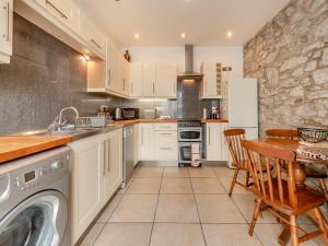 a kitchen with a washer and dryer and a table at Gwynfor in New Quay