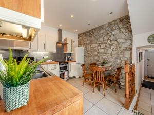 a kitchen with a table and a stone wall at Gwynfor in New Quay