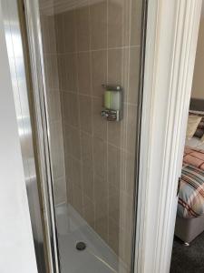 a shower with a glass door next to a bed at Oasis Abode @ Ashover Newcastle in Kenton