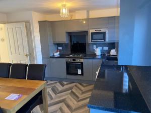 a kitchen with stainless steel appliances and a table at Oasis Abode @ Ashover Newcastle in Kenton