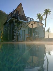 a house with an umbrella next to a swimming pool at Batur Homestay and Lodge in Bangli