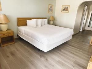 Hotel 191 - Moab في موآب: غرفة نوم بسرير ابيض وارضية خشبية