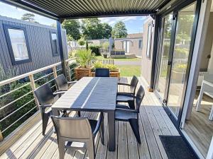 a wooden deck with a table and chairs on it at Mobil-Home Jullouville, 4 pièces, 6 personnes - FR-1-361A-5 in Jullouville-les-Pins