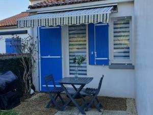 une table et des chaises devant un bâtiment avec des portes bleues dans l'établissement Maison La Faute-sur-Mer, 2 pièces, 4 personnes - FR-1-476-184, à La Faute-sur-Mer