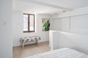 a white bedroom with a bed and a window at Le Nomade MTL in Montréal