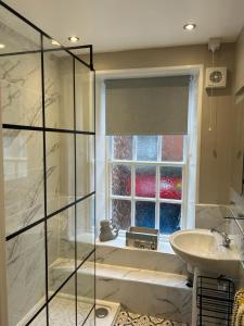 La salle de bains est pourvue d'une baignoire, d'un lavabo et d'une fenêtre. dans l'établissement 1 The Bookies Modern Apartment, Central Location, à Scarborough