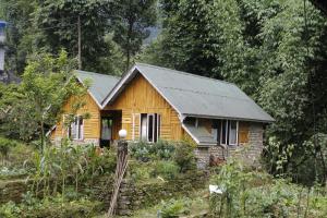 uma pequena casa de madeira no meio de uma floresta em Vamoose Cherry Resort em Pelling