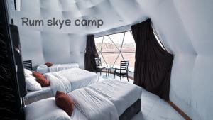 two beds in a room with a window at Rum Skye camp in Wadi Rum