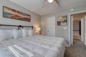 - une chambre avec un grand lit blanc et un ventilateur de plafond dans l'établissement 1408 Perrin Dr, Unit A - Ocean Walk Sleeps 8, à Myrtle Beach