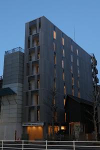 a black building with a tree in front of it at OHWA hostel minowa station in Tokyo