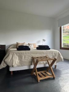 a white bedroom with a bed with a wooden table at Las Lavandas 2 in Ushuaia