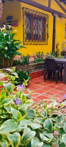 un jardín con un banco y flores frente a una casa amarilla en villa luz de vida en Silvia