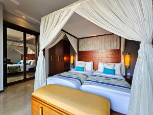 two beds in a bedroom with a canopy bed at Seminyak Icon - by Karaniya Experience - CHSE certified in Seminyak +81 photos