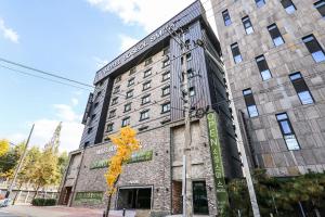 a building with a tree in front of it at Hotel Soseol Smith in Cheonan