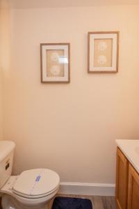 a bathroom with a toilet and two pictures on the wall at Multi-level Townhouse, Harvard, Mit, Red Line in Cambridge
