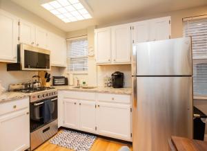 a kitchen with white cabinets and a stainless steel refrigerator at Multi-level Townhouse, Harvard, Mit, Red Line in Cambridge