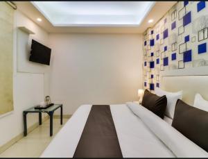 1 dormitorio con 1 cama y TV en la pared en Hotel Galaxy Stay B&B, en Nueva Delhi