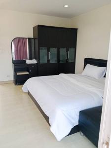 um quarto com uma cama branca e um armário preto em The Beach Bangsaen Condo 327/30 em Ban Bang Saen (1)