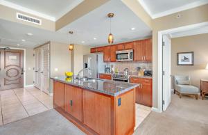 a kitchen with wooden cabinets and a counter top at KBM Resorts: Honua Kai HKK-820 Includes Rental Car in Kaanapali
