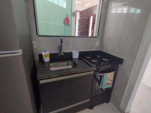 een kleine keuken met een spoelbak en een fornuis bij Solares le Bien apartamento proxímo a praia in Búzios