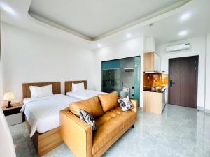 a bedroom with a bed and a couch and a kitchen at Sea Flower Homestay in Quy Nhon