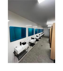 Capsuleaccom Hostel في غولد كوست: صف من المغاسل في حمام مع نوافذ زرقاء