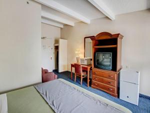 a hotel room with a bed and a tv and a desk at Scottish Inn Whippany in Whippany