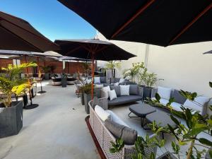 eine Terrasse mit Sofas, Tischen und Sonnenschirmen in der Unterkunft Capsuleaccom Hostel in Gold Coast