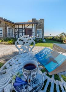 a cup of coffee sitting on a table with a book at Dover Cottage in Nuwara Eliya