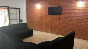 a living room with a couch and a brick wall at Hostel do Cabral in Piracicaba