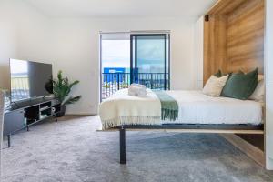 a bedroom with a bed and a large window at Upper Studio Perfection: 8 Wilmer St. Gem in Christchurch