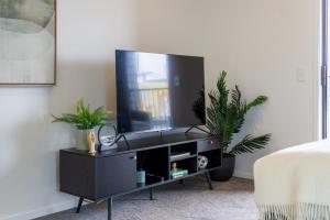 a living room with a tv on a black entertainment center at Upper Studio Perfection: 8 Wilmer St. Gem in Christchurch