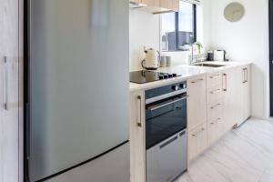 a kitchen with a stainless steel refrigerator and white counters at Upper Studio Perfection: 8 Wilmer St. Gem in Christchurch