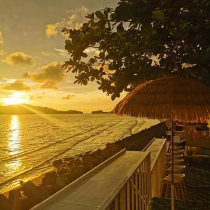 a beach with a straw umbrella and the ocean at Amanda อามันดา in Ban Pak Ba Ra