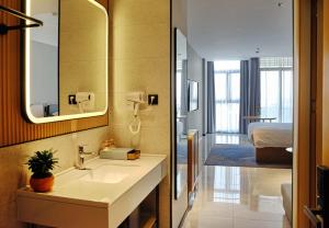 La salle de bains est pourvue d'un lavabo, d'un miroir et d'un lit. dans l'établissement CitiGo HOTEL - 越南平阳新渊欢阁酒店, 