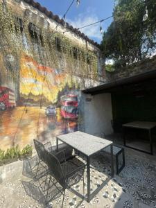 a table and chairs in front of a wall with a painting at The Hostal Pub Antigua Guatemala in Antigua Guatemala