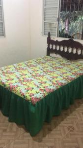 een bed met een groene deken met bloemen erop bij Chácara Flor do Campo in Leopoldina