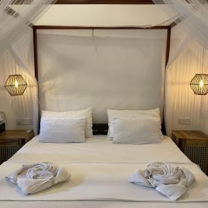 uma cama com lençóis brancos e duas toalhas em Agra Arugambay em Baía de Arugam