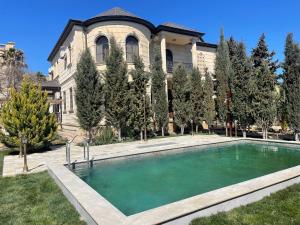 a house with a swimming pool in front of a building at Green Garden Shuvelan in Baku