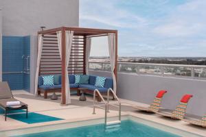 a pool on the roof of a building with chairs and a table at Aloft Fort Lauderdale Airport in Fort Lauderdale