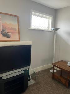 a living room with a flat screen tv and a table at Shared 4 Bedroom House in South Bend