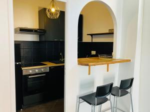 uma cozinha com armários pretos, um balcão e bancos em Appartement cosy aux portes de Paris em Montreuil