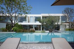 a swimming pool with two chairs in front of a building at Top sea villa in Ban Bo Yai