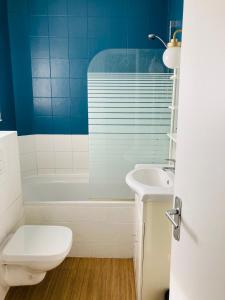 a bathroom with a toilet and a tub and a sink at Appartement cosy aux portes de Paris in Montreuil