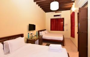 a hotel room with two beds and a television at Villa Dumont in Puducherry