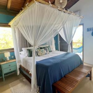 a bedroom with a canopy bed with a wooden bench at Casa Uluwatu - Barra Grande - Bahia in Marau