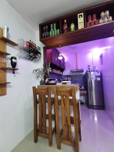 a kitchen with a bar with two chairs and a refrigerator at Homelux Transient House in Cauayan City