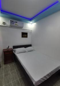1 dormitorio con cama blanca y techo azul en Homelux Transient House en Ciudad de Cauayán
