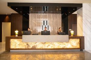 three people sitting at a reception desk with laptops at Amber Hotel - Cebu in Cebu City