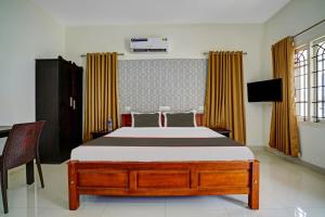 1 dormitorio con 1 cama y TV en Collection O Lux villa en Nedumbassery